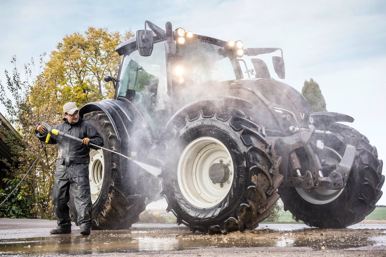 mężczyzna myje brudny traktor myjką ciśnieniową Karcher